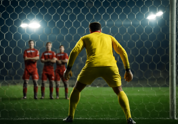 Kiper bersiap menghadapi tendangan bebas dengan tembok pemain bertahan